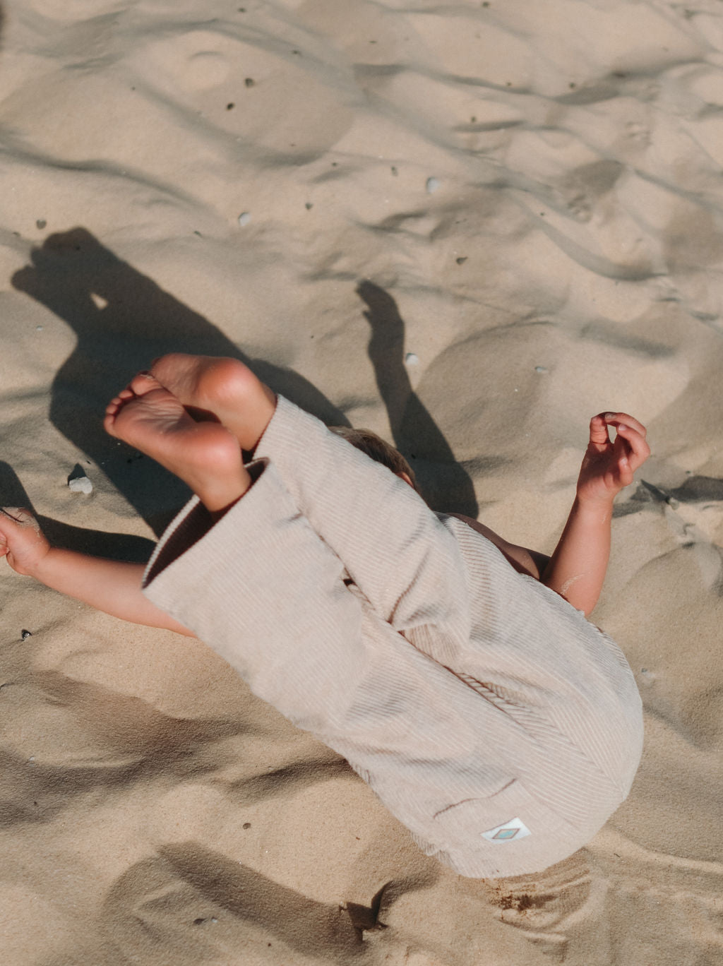 child wearing beige corduroy pants playing on sand